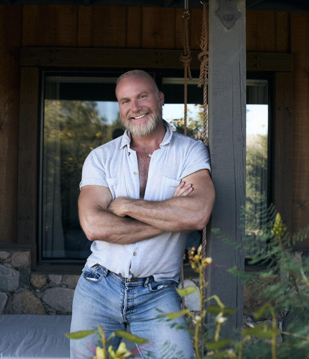 Court Vox, lead facilitator and founder of The Bodyvox, standing on a cabin porch.